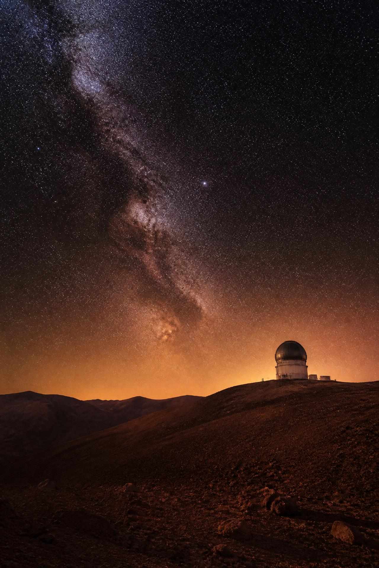 Céu estrelado com a via láctea sobre o deserto do Atacama e a silhueta de um observatório