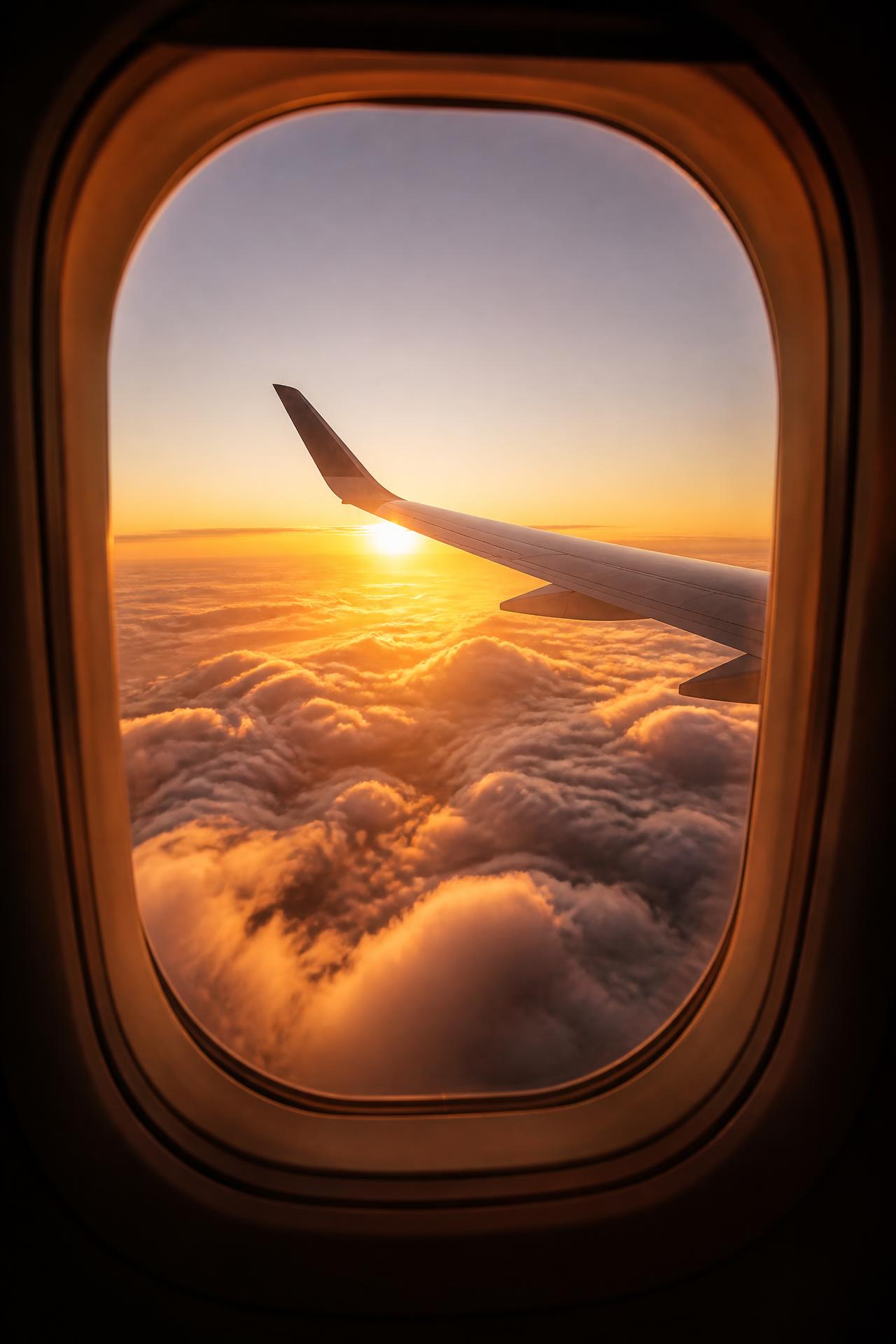 Nascer do sol visto da janela de um avião, com nuvens douradas